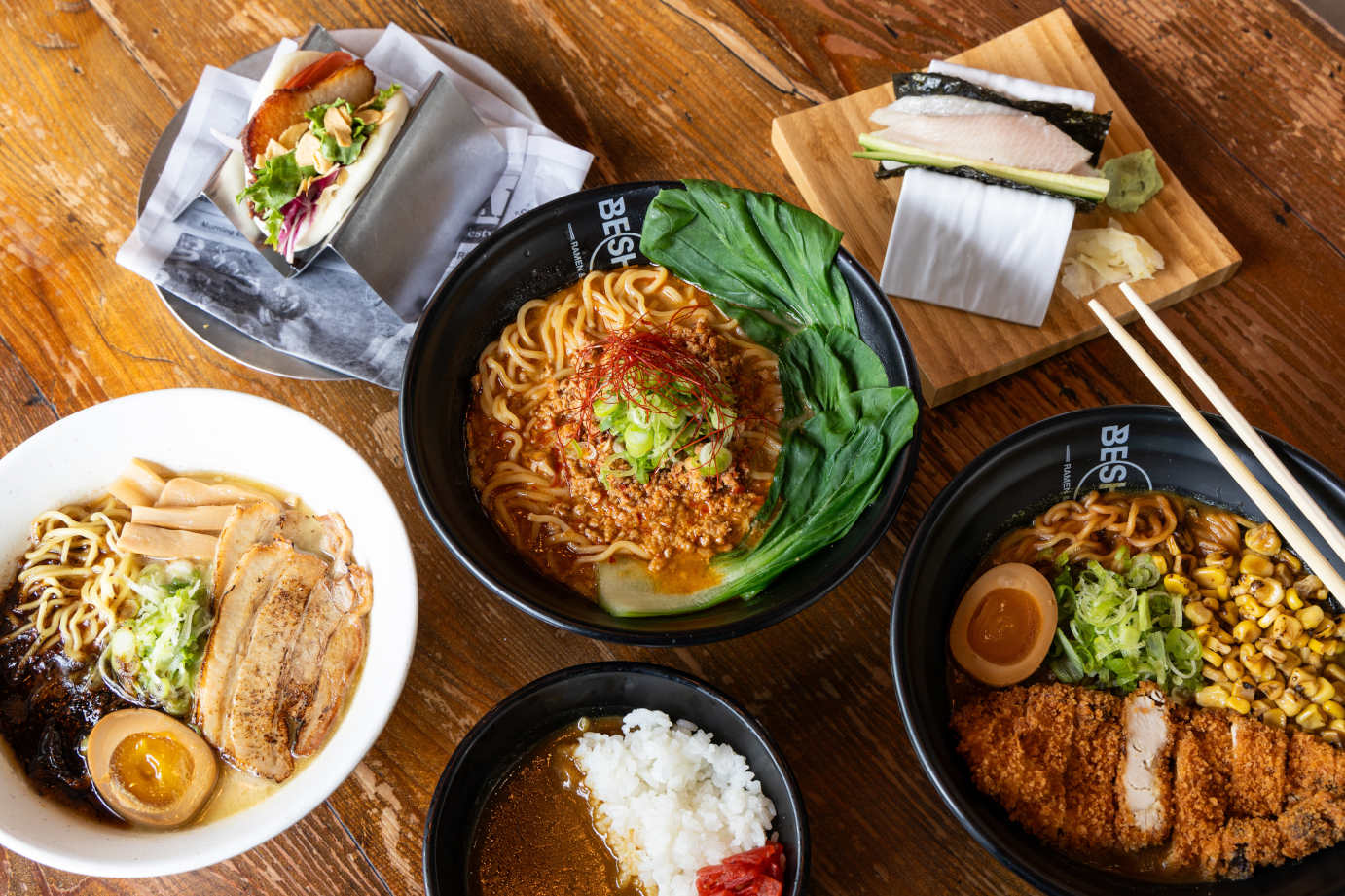 A table adorned with multiple bowls of diverse food items and chopsticks, ready for a shared culinary experience.